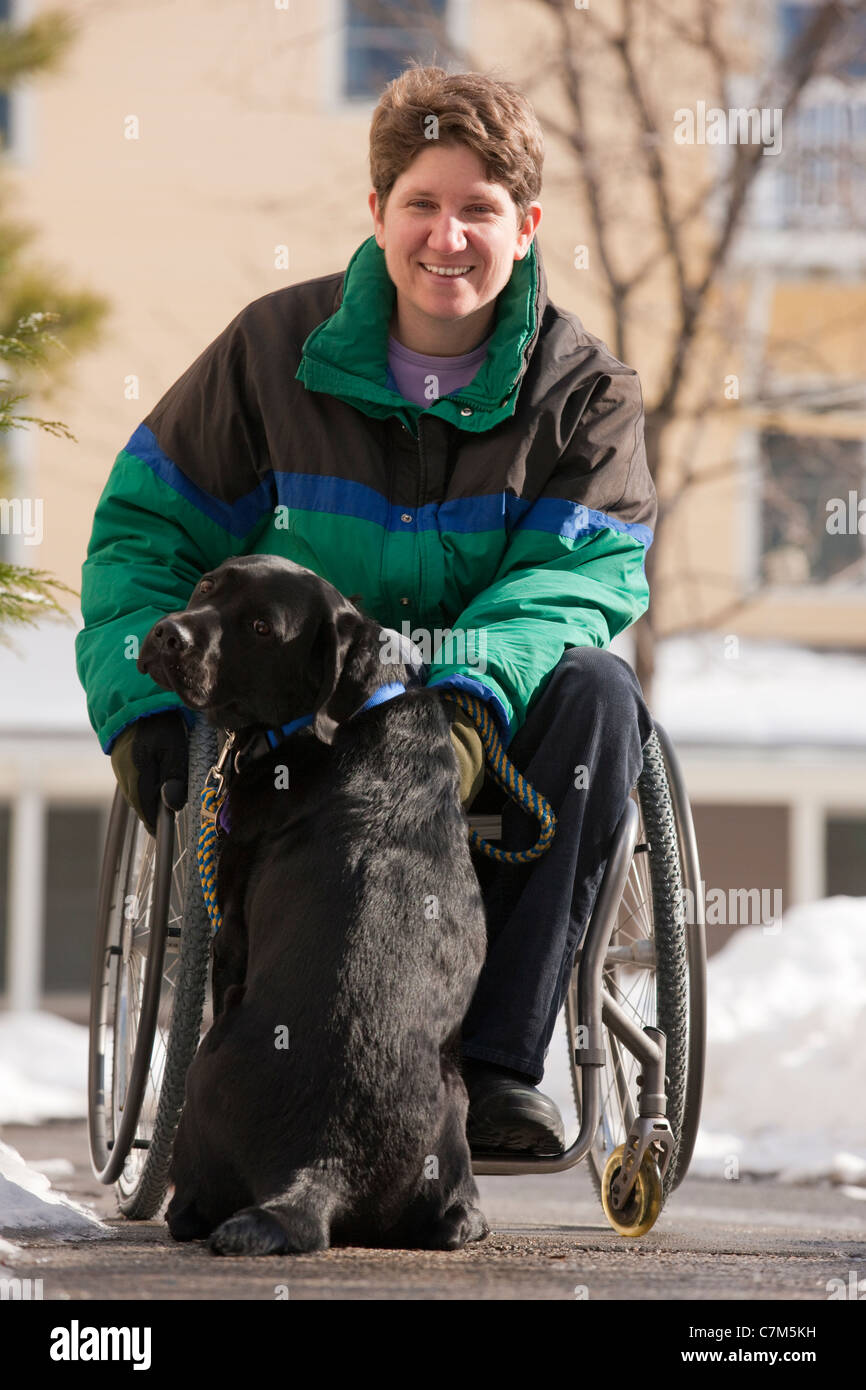 Donna con sclerosi multipla a giocare con un cane di servizio Foto Stock