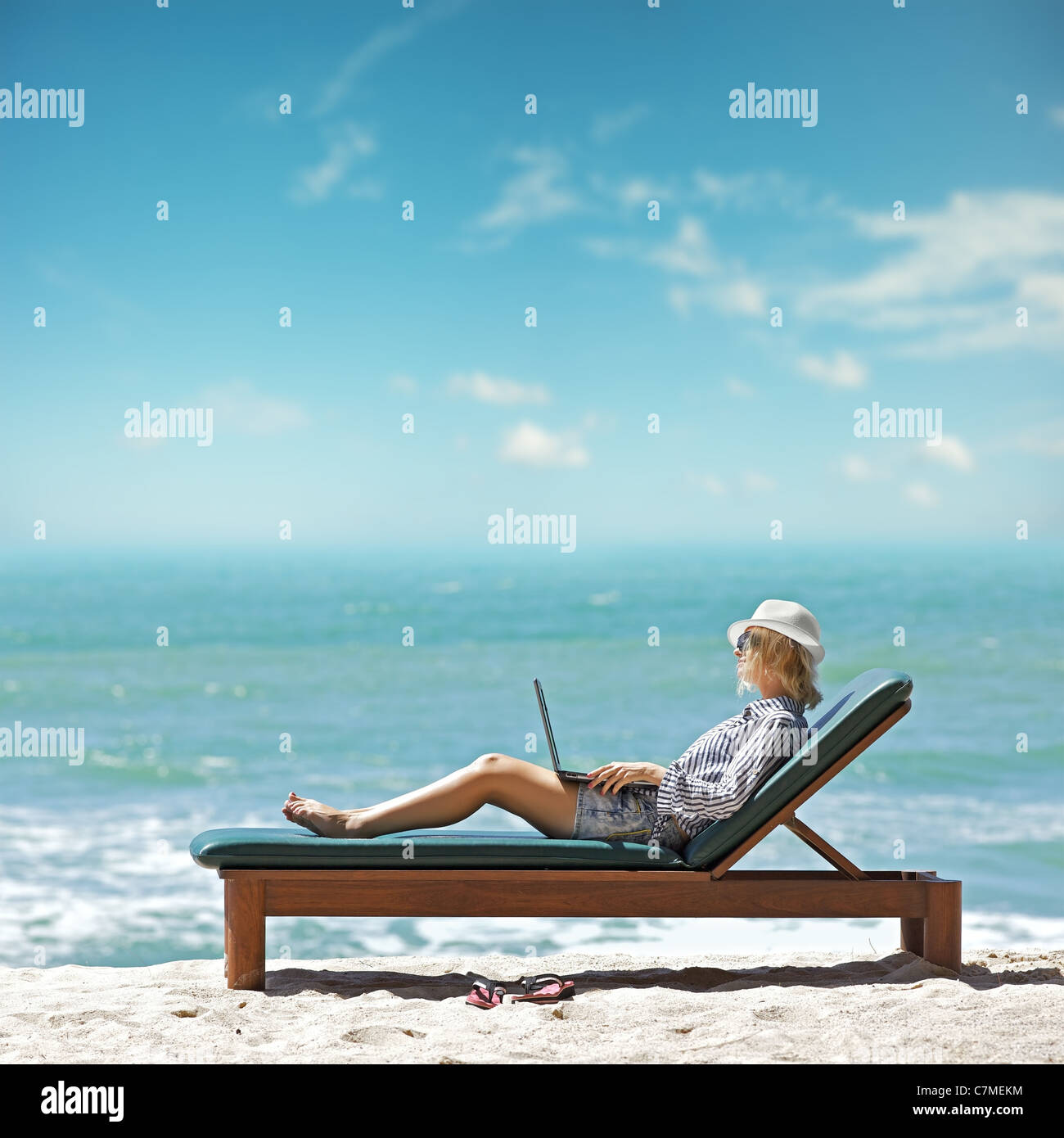 Giovane donna con il portatile in spiaggia Foto Stock