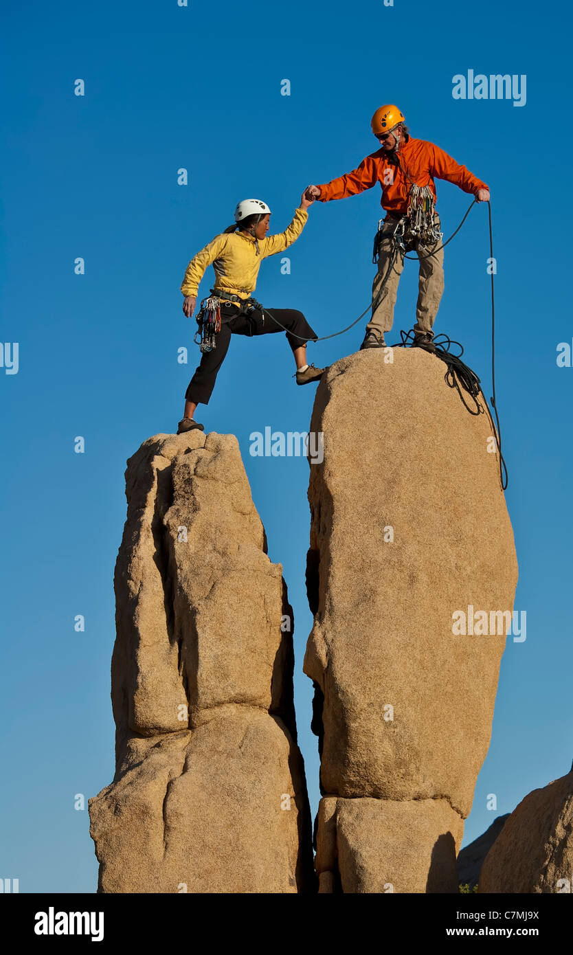 Team di arrampicatori lotta per raggiungere il vertice di un impegnativo pinnacle. Foto Stock
