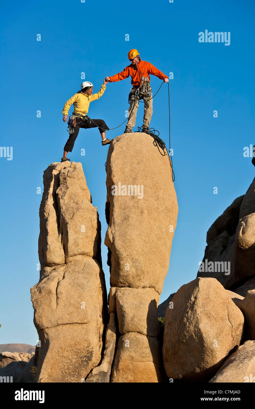 Team di arrampicatori lotta per raggiungere il vertice di un impegnativo pinnacle. Foto Stock