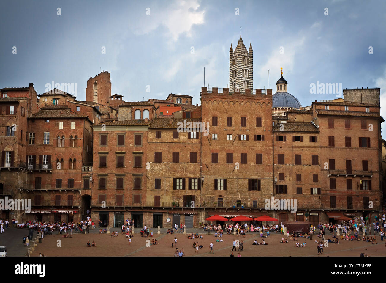 Vista Il Campo Siena Italia con la torre e la cupola del Duomo in background e turisti in primo piano. Foto Stock