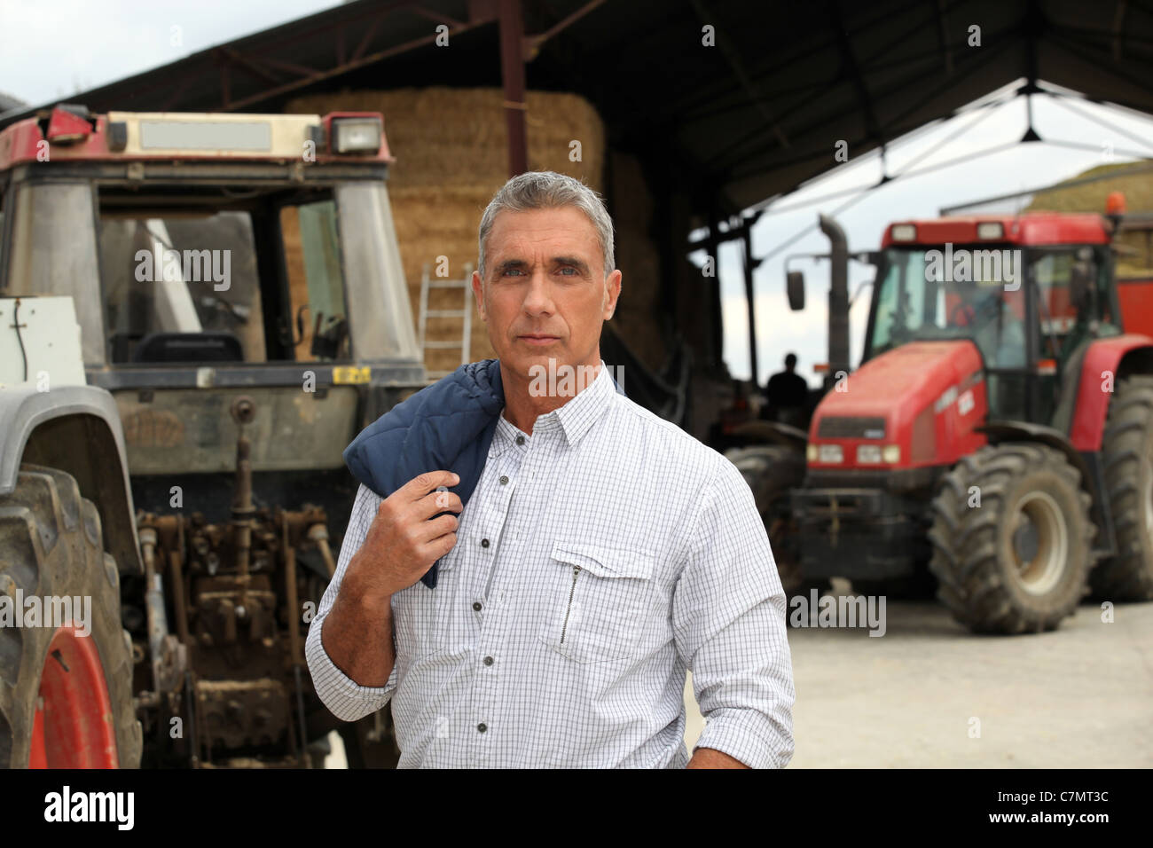 Un agricoltore che posano con i suoi trattori Foto Stock