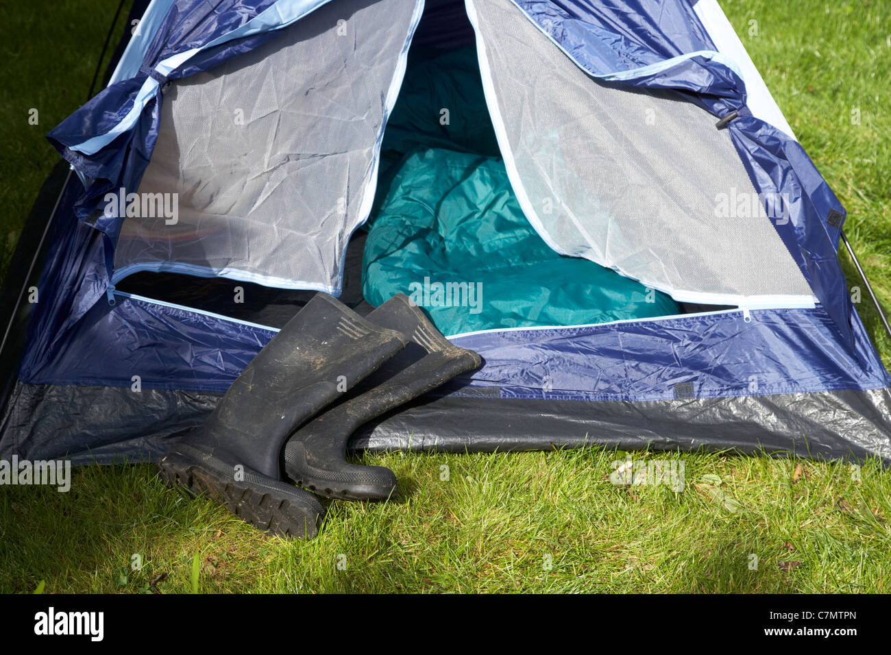 Sporchi stivali da pioggia disteso di fronte a un open tenda Foto Stock