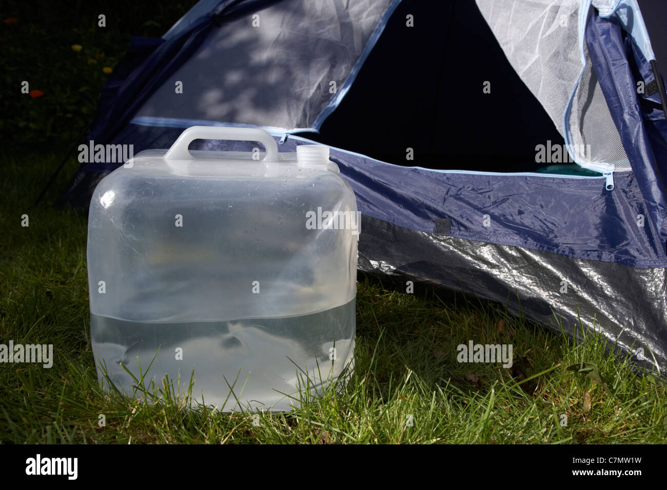 Contenitore di acqua al di fuori seduta una mezza porta anteriore aperta di una tenda in un campo Foto Stock