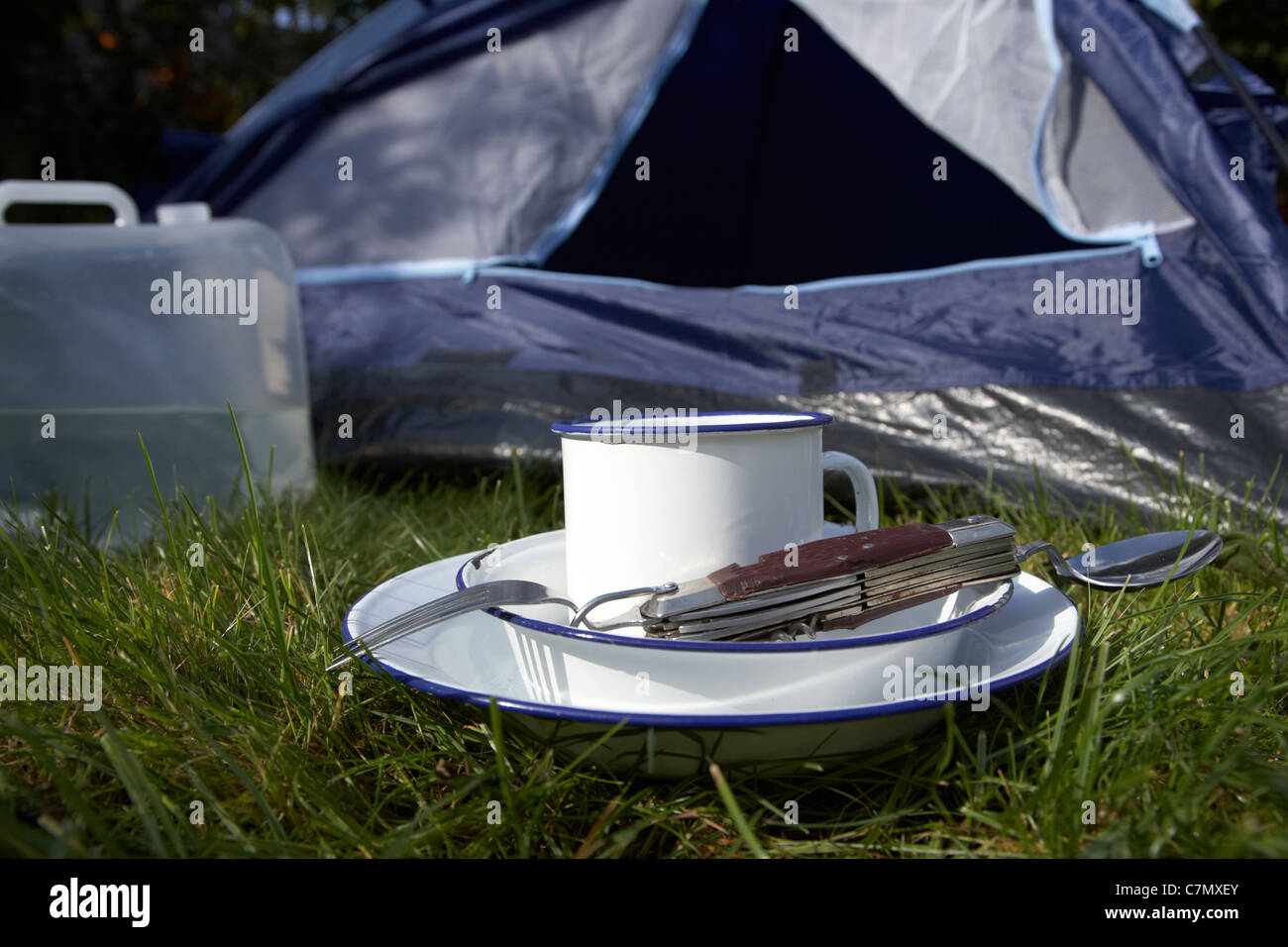 Contenitore di acqua latta Cup e il campeggio utensili utensile davanti alla porta aperta di una tenda Foto Stock
