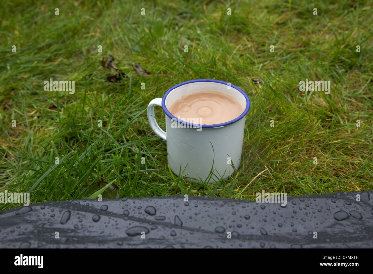 La tazza di tè con pioggia caduta in essa al di fuori della parte anteriore di una tenda Foto Stock