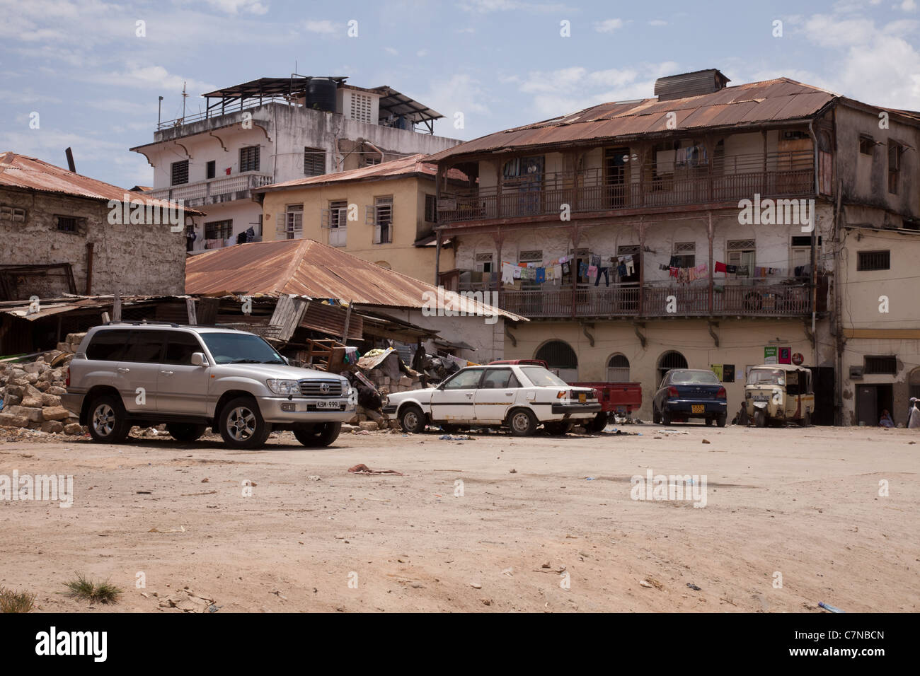 SUV parcheggiata tra le auto vecchie e macerie a la città vecchia di Mombasa, sito patrimonio mondiale dell'UNESCO, Kenya, Africa Foto Stock