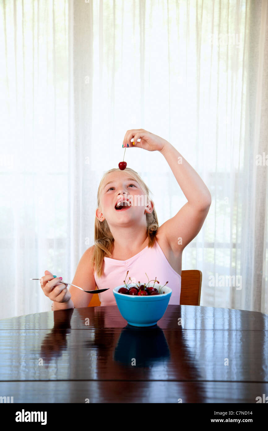 Bambina di mangiare le ciliegie da un vaso Foto Stock