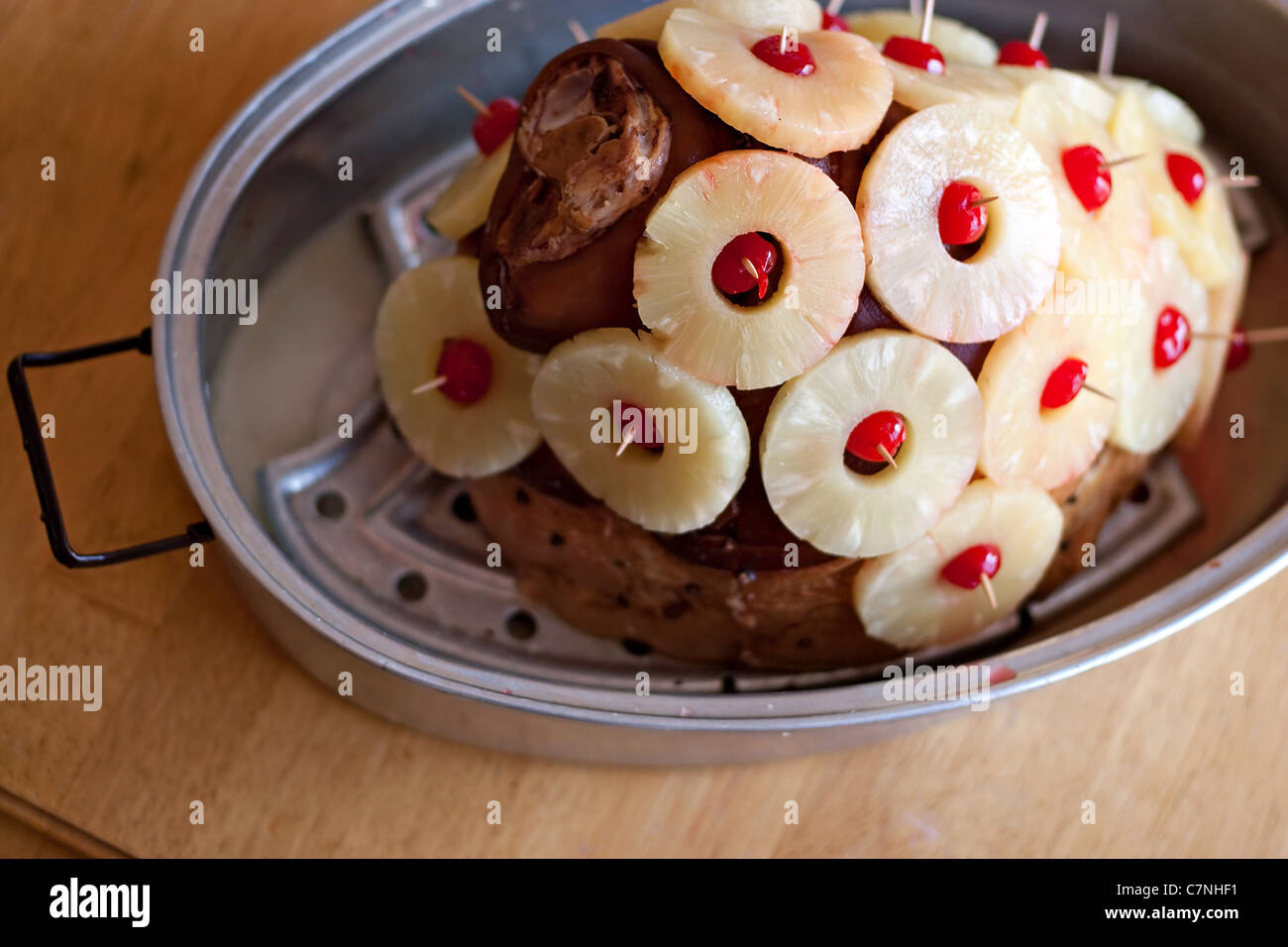 Un grande prosciutto tutto guarnito con gli anelli di ananas e ciliegie preparato e pronto per cuocere. Foto Stock