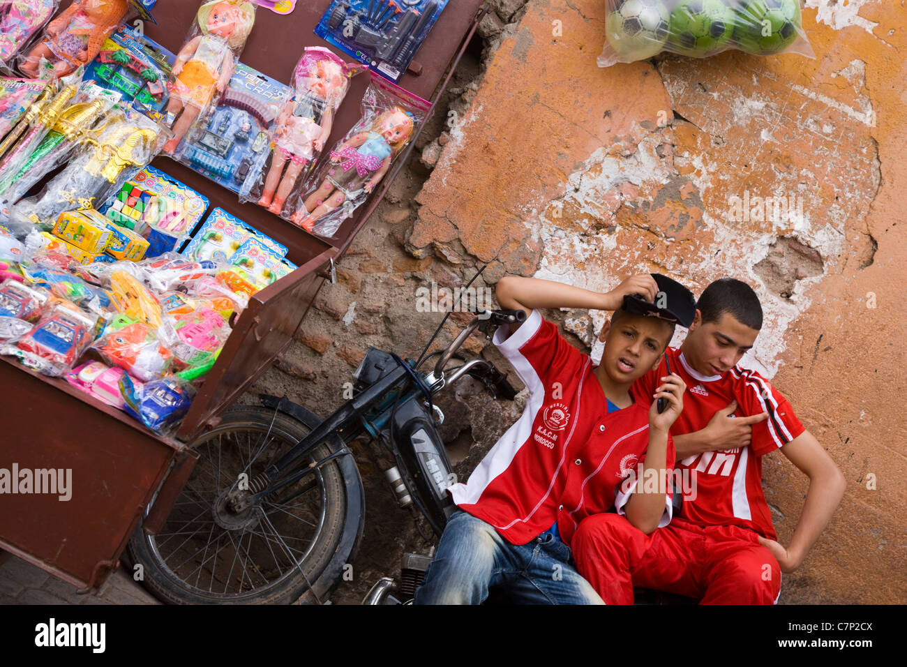 Due giovani ragazzi in magliette da calcio seduto su un ciclomotore nel souk marocchino Foto Stock