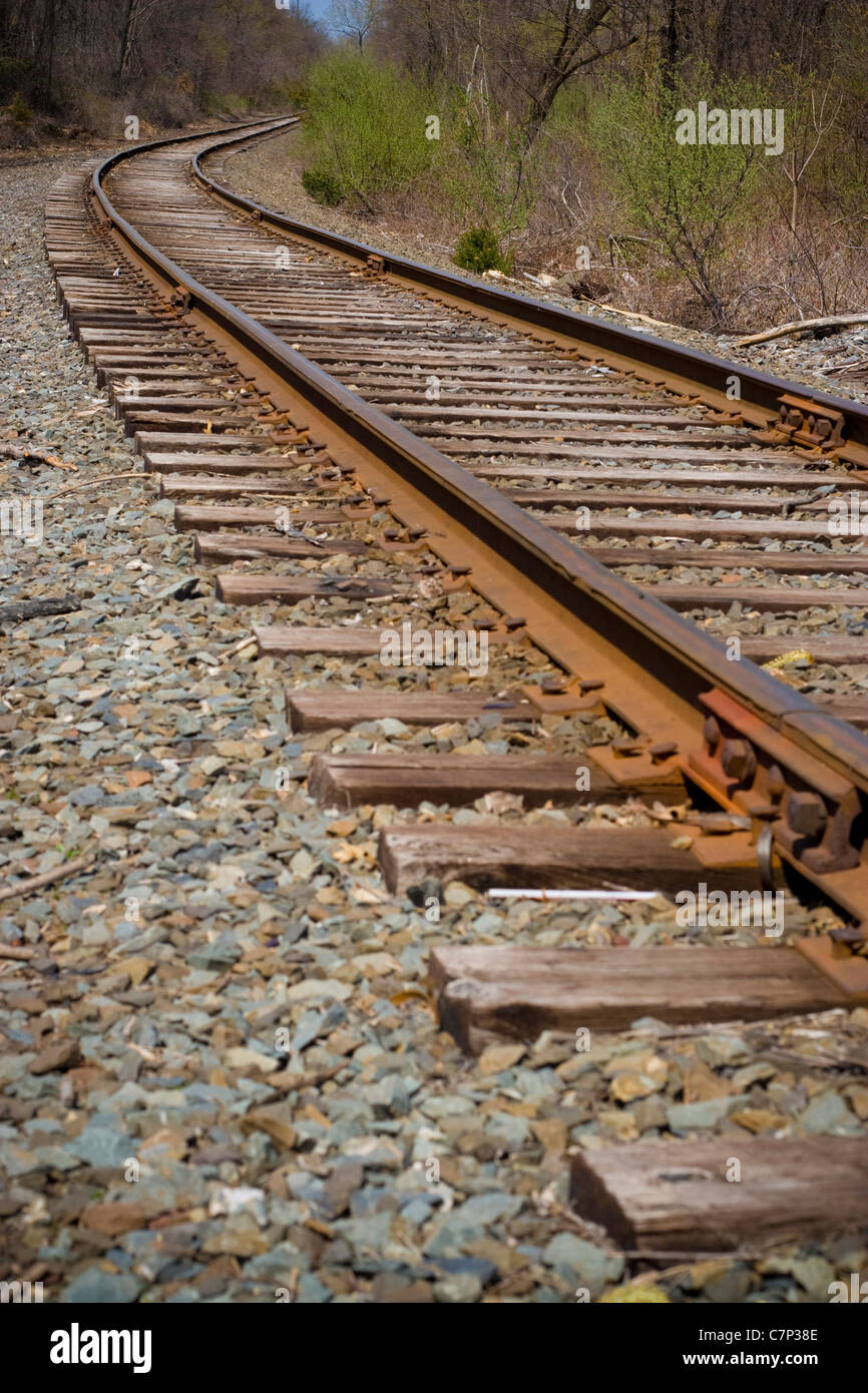 I binari della ferrovia della curvatura fuori nella distanza avanti. Foto Stock
