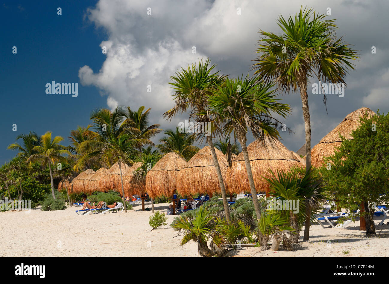 Riviera Maya spiaggia di sabbia bianca con ombrelloni di paglia e di palme e un imminente temporale nuvole Messico Foto Stock