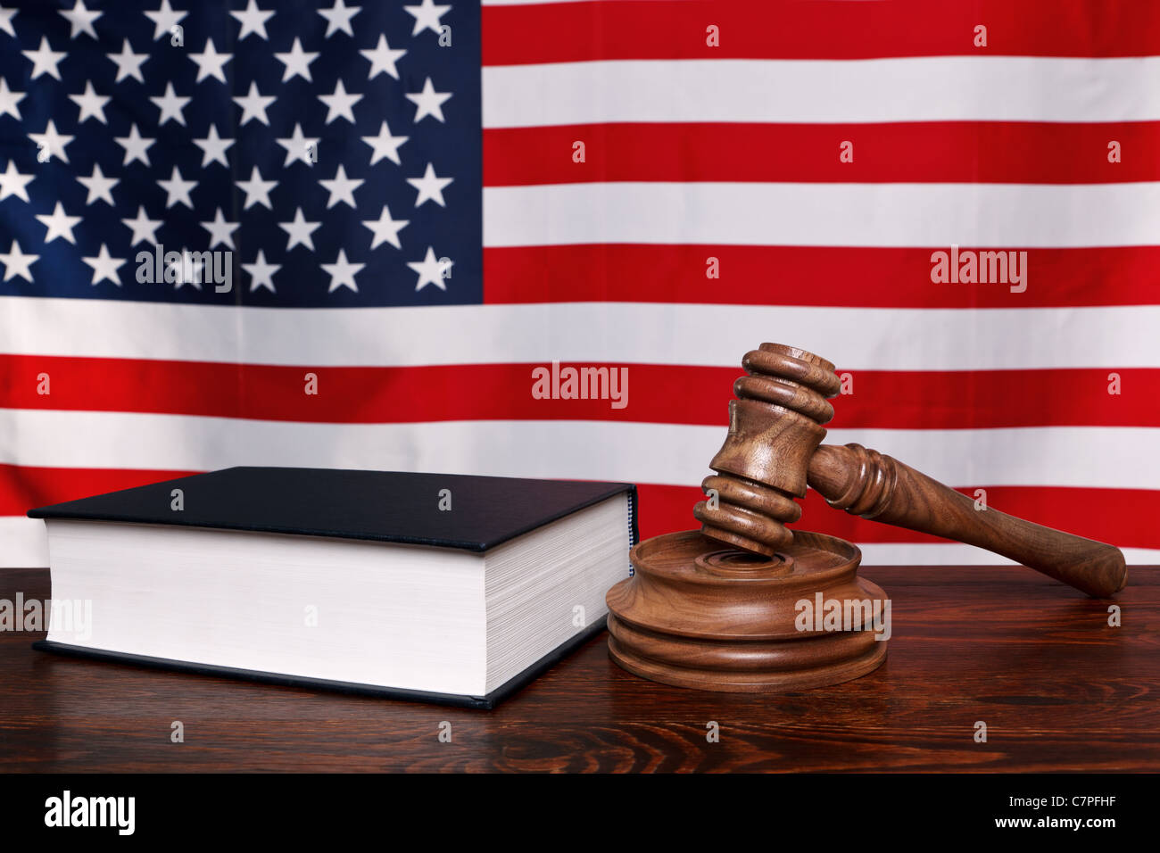 Still Life foto di un martello, il blocco e la legge libro su un banco di giudici con la bandiera americana dietro. Foto Stock