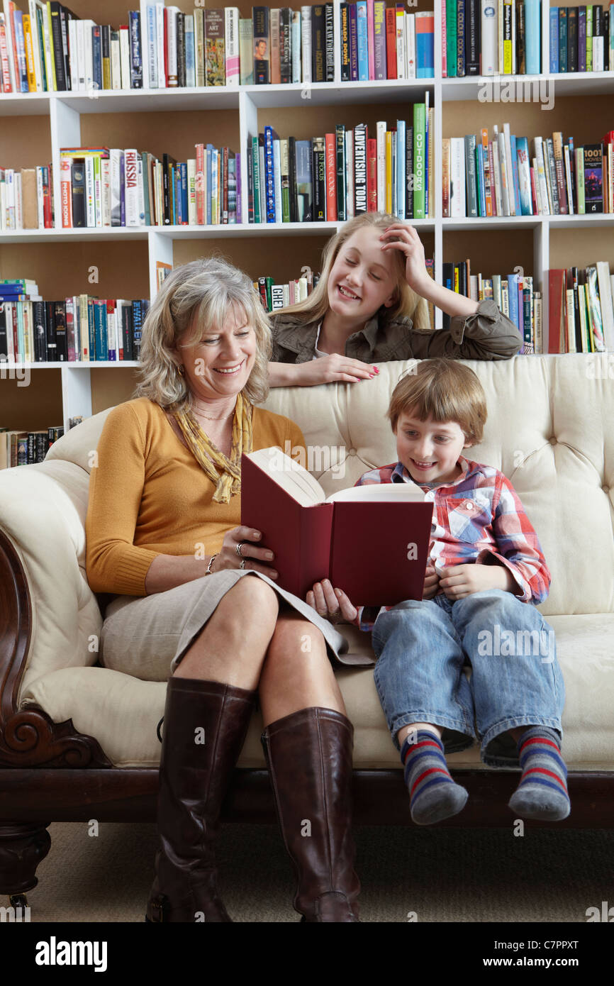 Donna e nipoti insieme di lettura Foto Stock