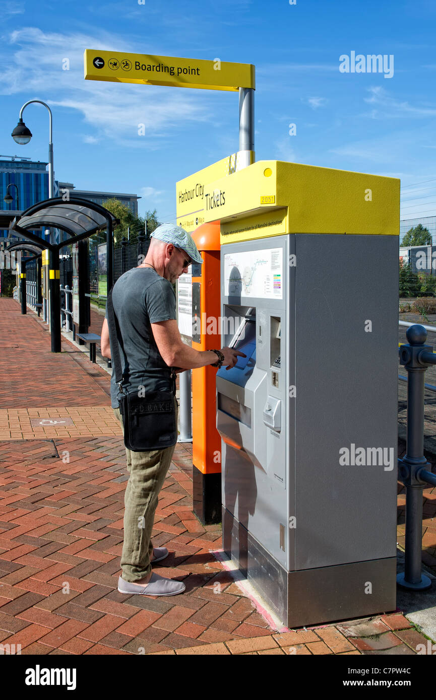 Giovane uomo acquisto biglietto per utilizzare il tram Metrolink sistema in Salford Quays vicino a Manchester, Inghilterra Foto Stock