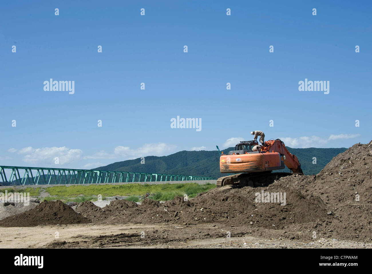 Un lavoratore salite a bordo di un escavatore deselezionando le macerie fuori Okawa scuola elementare di Ishinomaki City Foto Stock