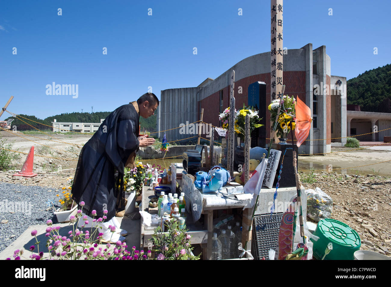 Un prete buddista offre la preghiera al di fuori Okawa scuola per i 74 bambini e insegnanti che sono stati uccisi durante il mese di marzo tsunami Foto Stock