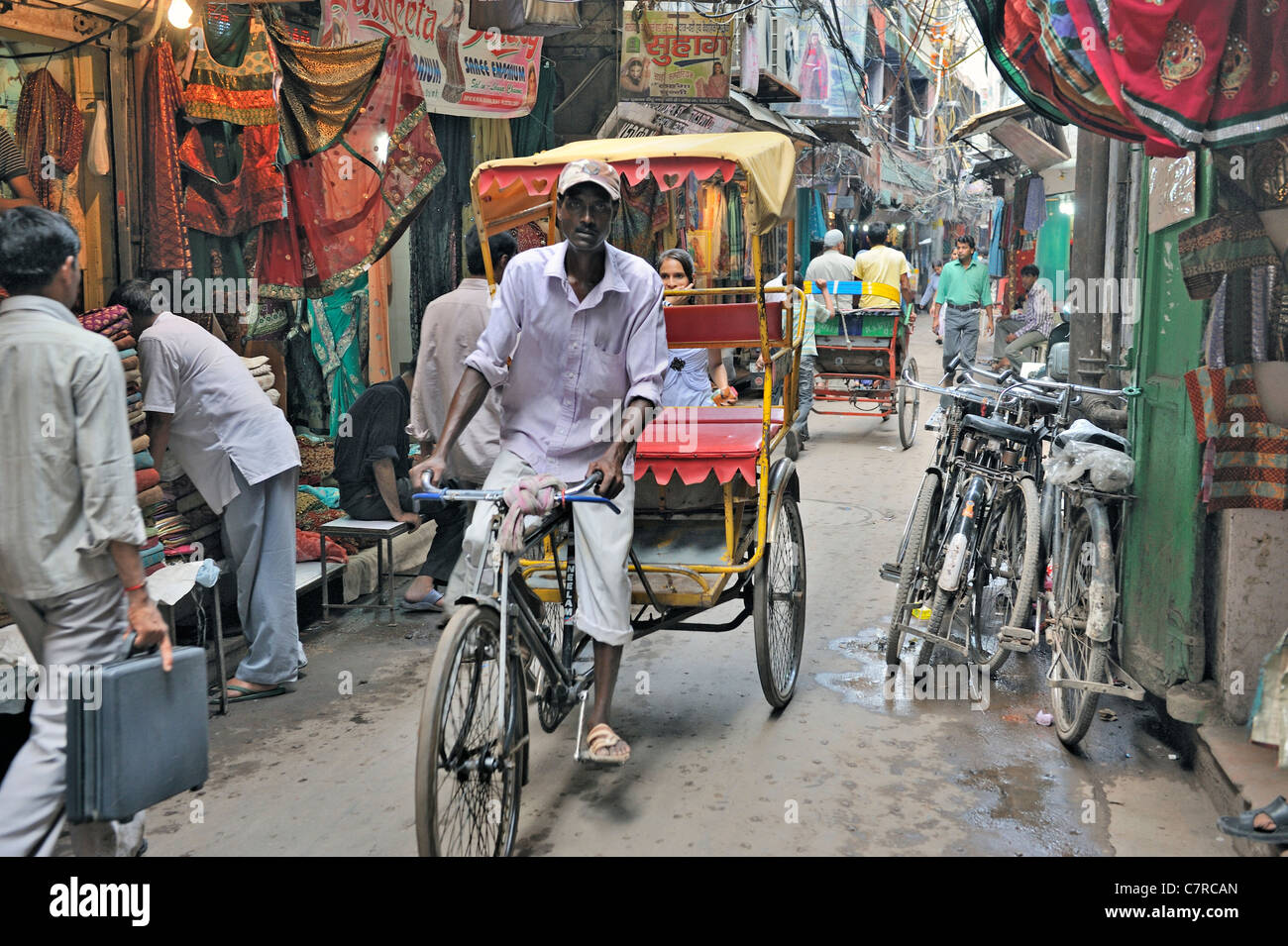 In rickshaw driver passando attraverso il mercato della seta nella Vecchia Delhi Foto Stock