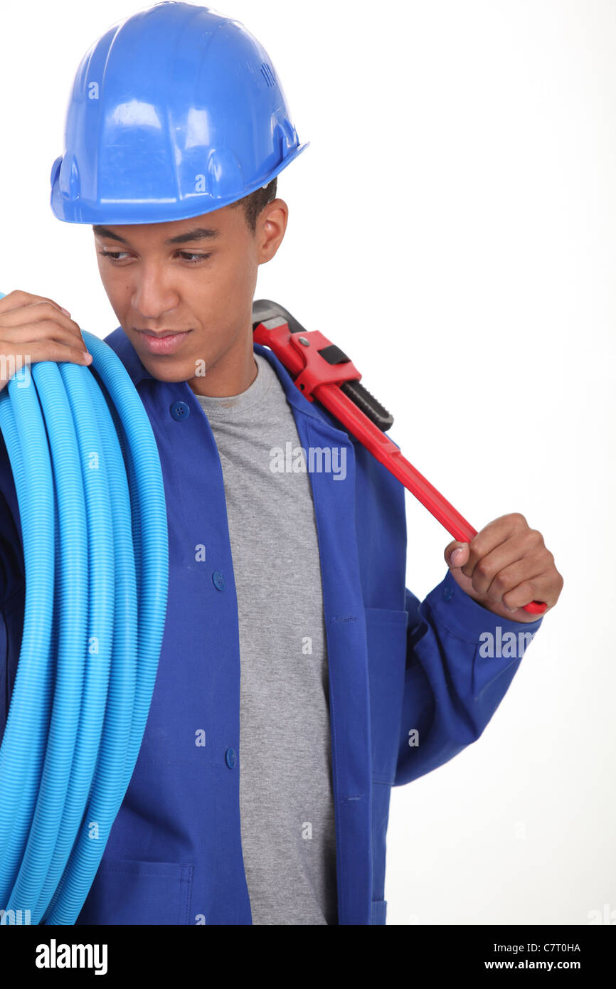 Giovane lavoratore con blu tubo flessibile e una chiave Foto Stock