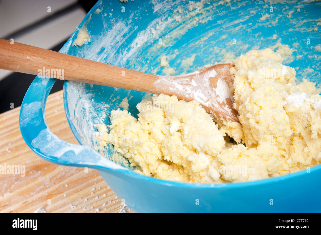 Un blu vaschetta di miscelazione con la miscela e il cucchiaio di legno Foto Stock