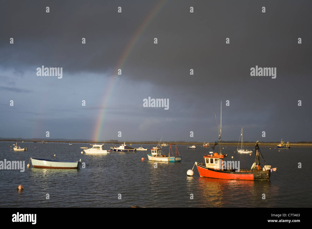 Un arcobaleno sopra l'acqua in un meditabondo, cielo tempestoso. Foto Stock