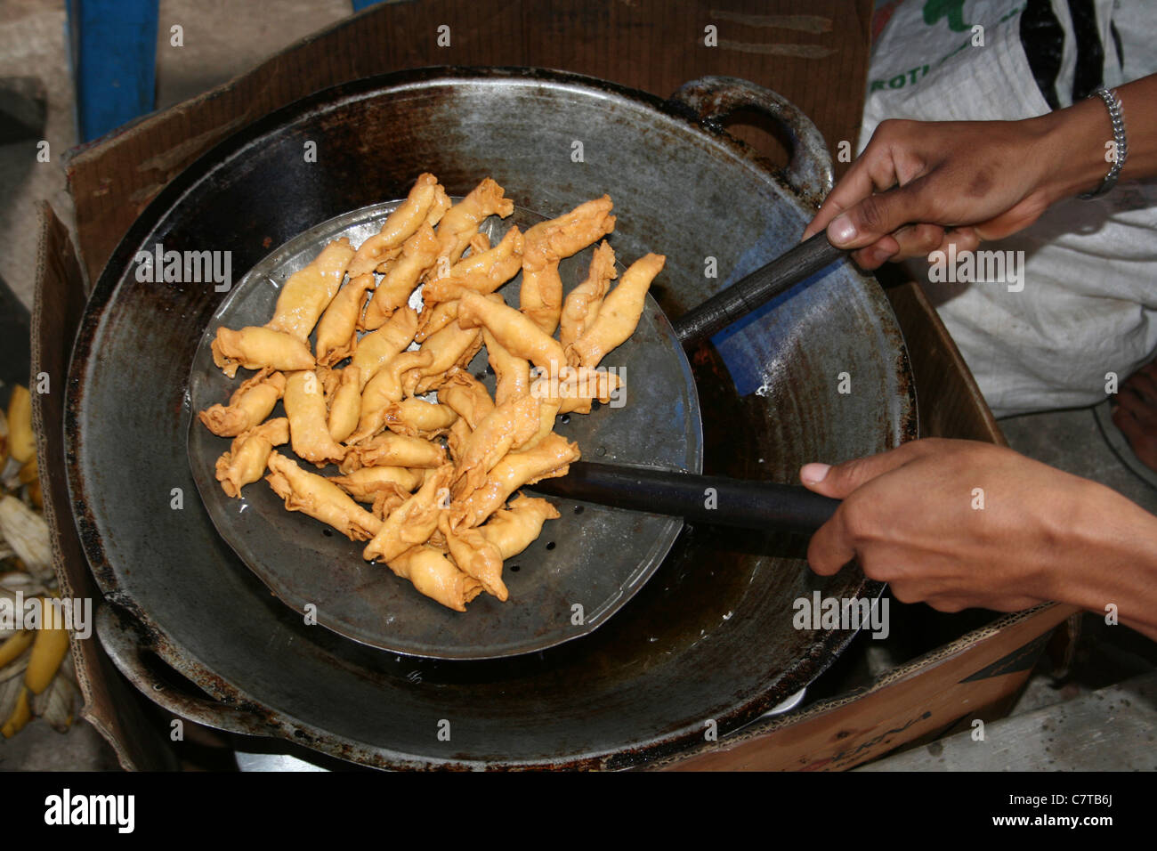 Spuntini per friggere in una padella in un mercato indonesiano Foto Stock