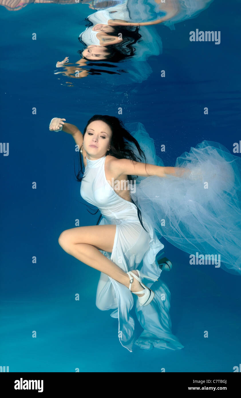 Una giovane donna con grandi capelli in posa di un subacqueo in piscina Foto Stock