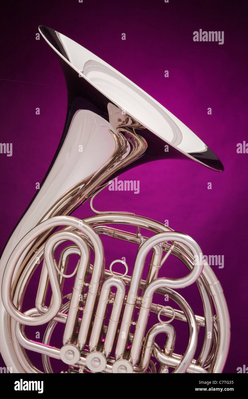 Un professional double corno francese isolati contro un faretto viola sfondo. Foto Stock