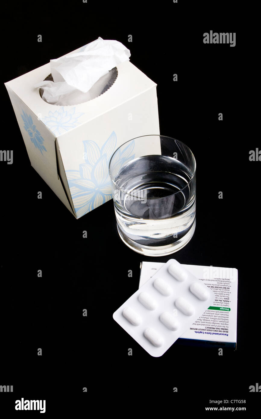 Bustina di compresse, bicchiere di acqua e una scatola di tessuti Foto Stock
