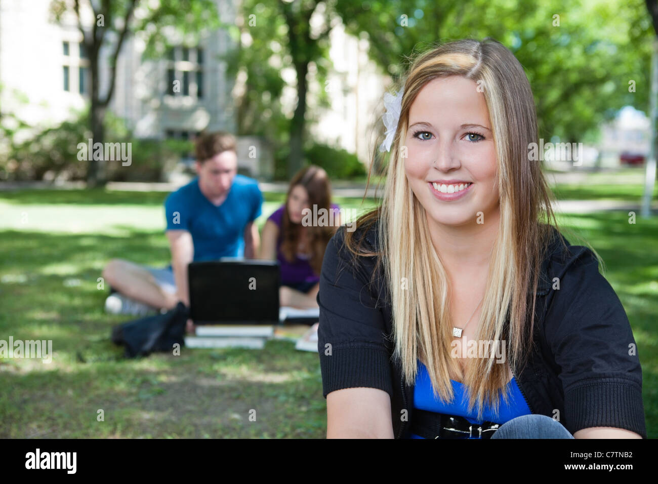 Ritratto di felice ragazza adolescente con i compagni di classe in background Foto Stock