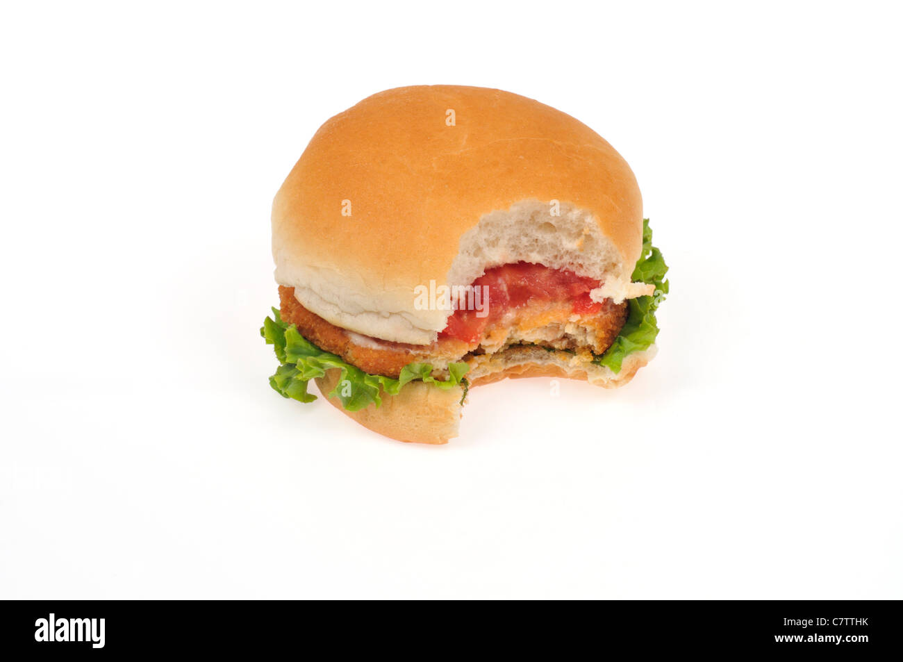 Pollo Impanato patty sandwich in un panino con lattuga, pomodoro e un morso preso fuori di esso su sfondo bianco, isolata. Foto Stock