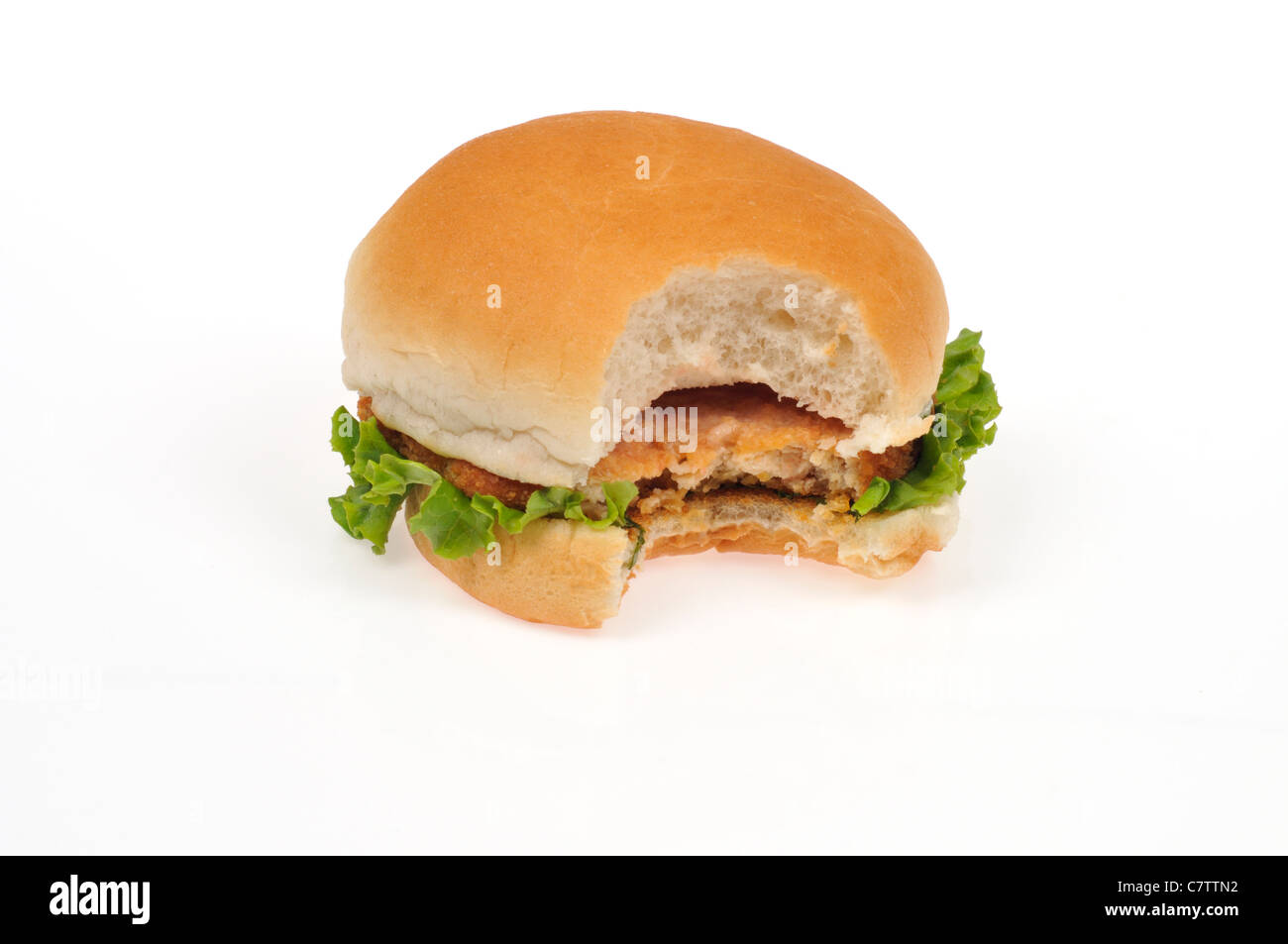Pollo Impanato patty sandwich in un panino con lattuga e un boccone fuori di esso su sfondo bianco, ritaglio. Foto Stock