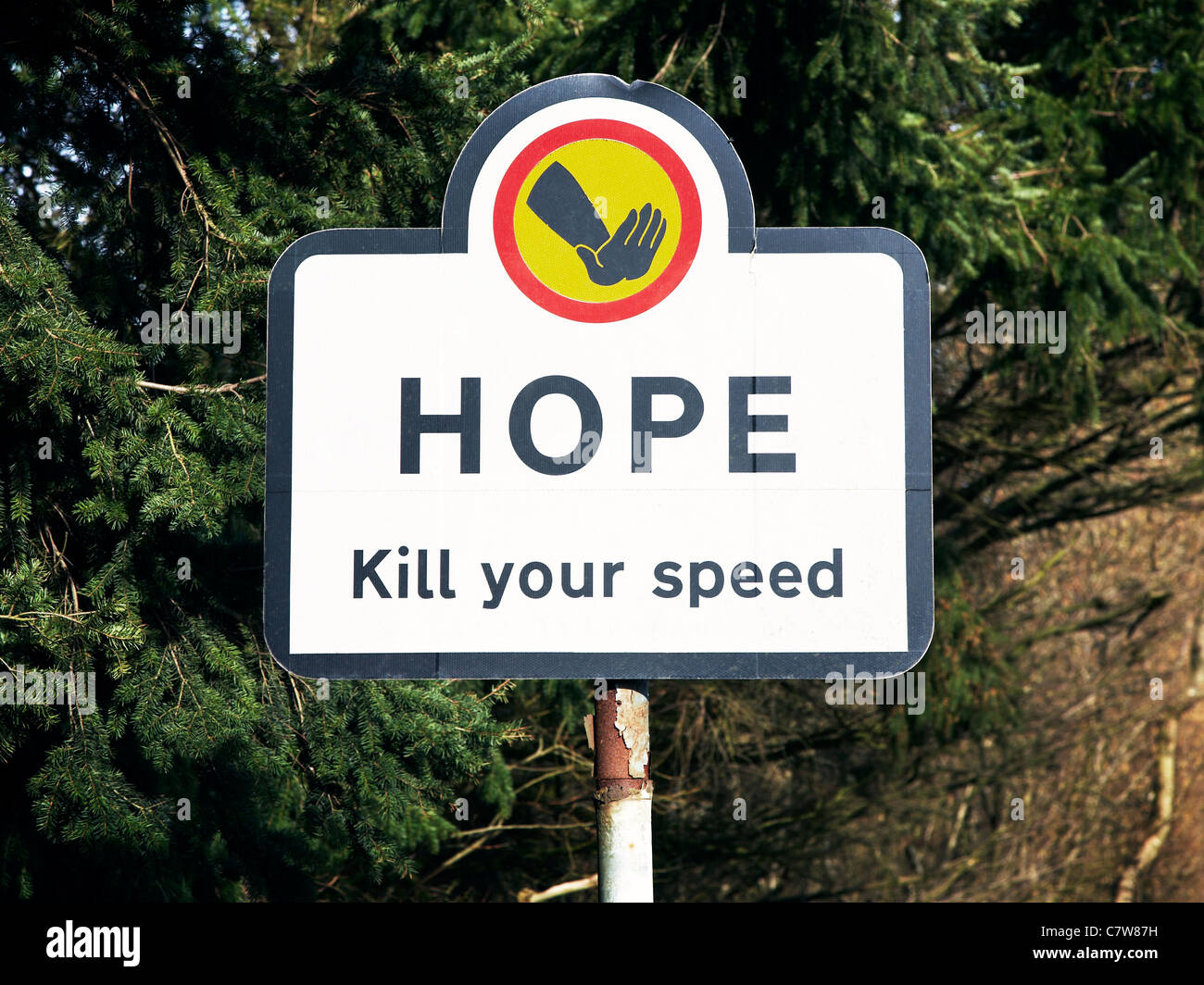 Cartello stradale dal Villaggio della Speranza dicendo la speranza di uccidere la tua velocità contro lo sfondo di albero Foto Stock
