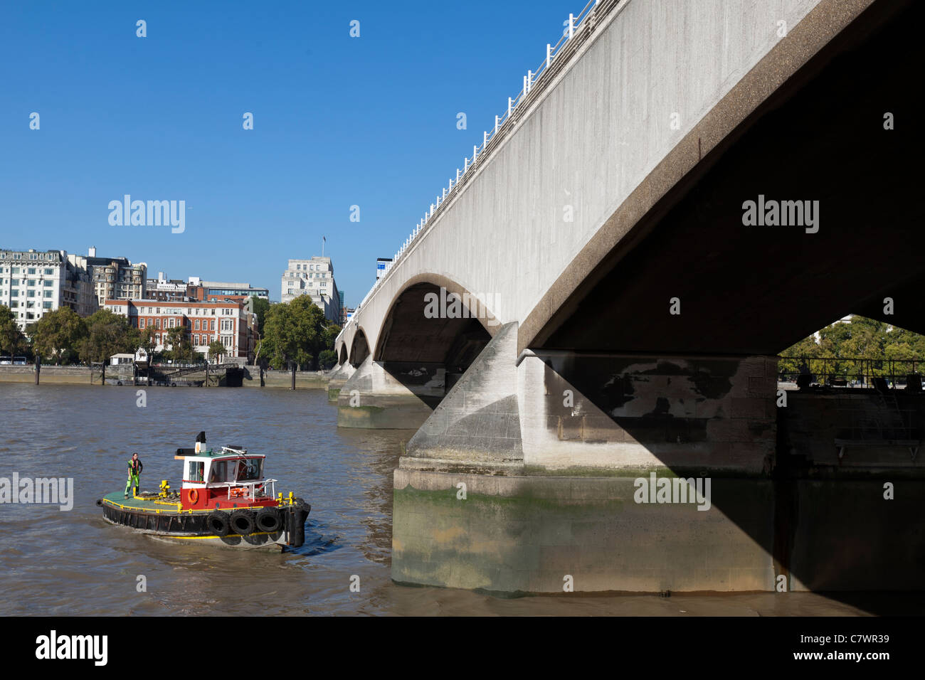 Una piccola barca esaminando uno dei piloni del ponte di Waterloo, preso dal Southbank, Londra, Regno Unito. Foto Stock