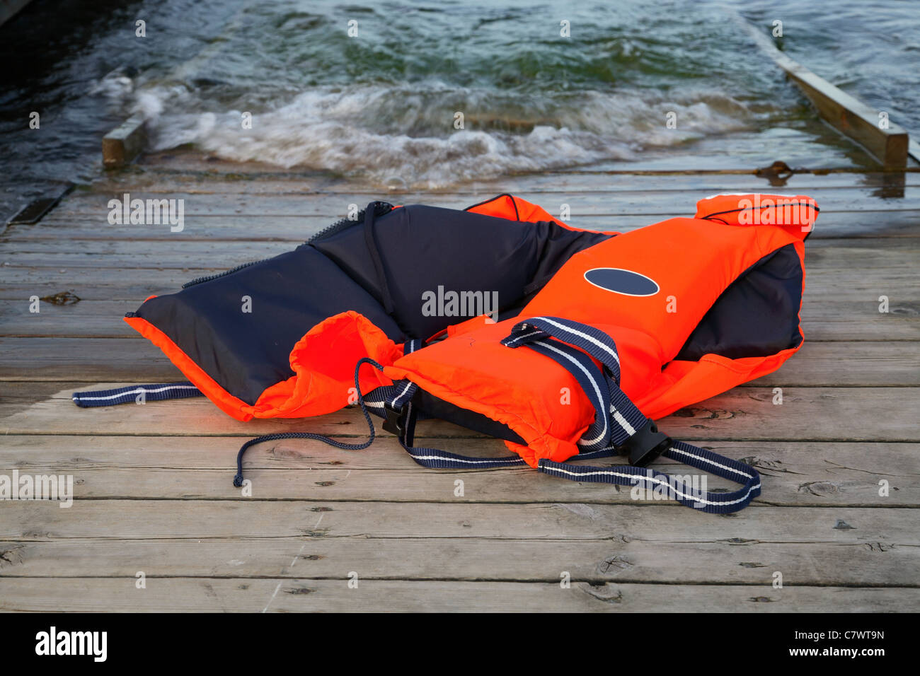 Abbandonata, rosso giubbotto di salvataggio per sport acquatici gettato su una rampa in barca Foto Stock