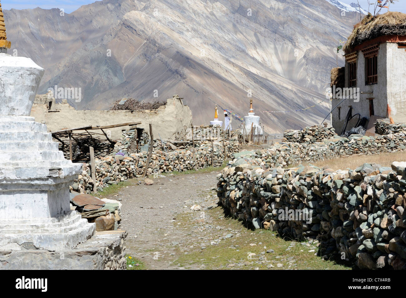 Una via si snoda passato piatto tradizionale con tetti di case e chortens, gli stupa, tra muri in pietra a secco nel villaggio di Rangdum Foto Stock