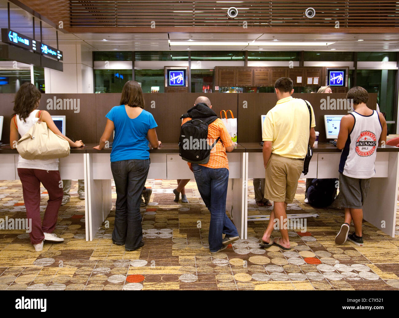 I passeggeri del trasporto aereo che utilizzano il computer nella sala partenze, l'Aeroporto Changi di Singapore asia Foto Stock