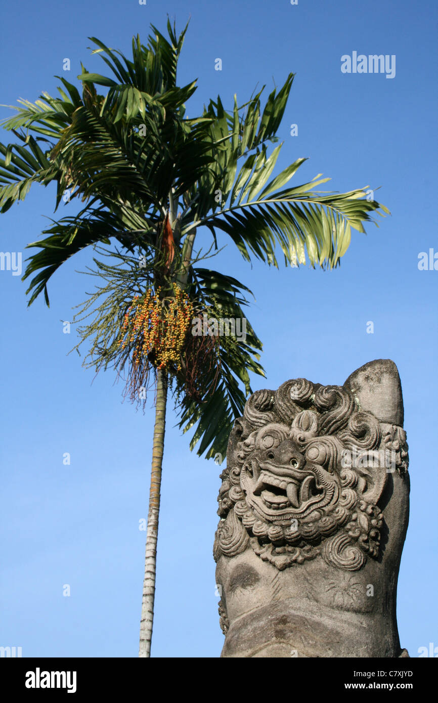 Il demone di pietra al fianco di noci di arec Palm Tree Foto Stock