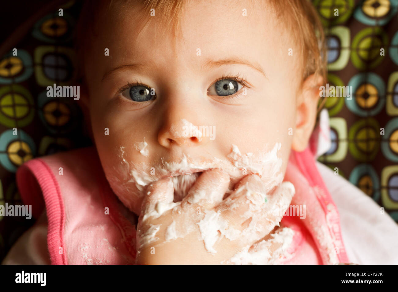 Baby girl facendo un pasticcio mentre si alimenta se stessa torta Foto Stock