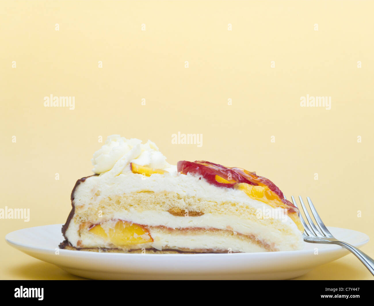 La torta di panna con pesche su giallo Foto Stock