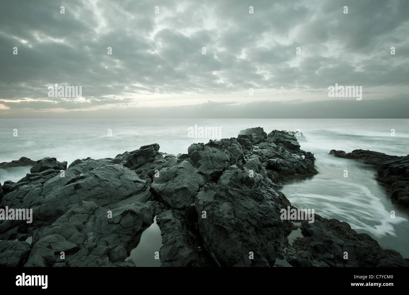 Marea come movimento sfocate su una spiaggia rocciosa al crepuscolo Foto Stock