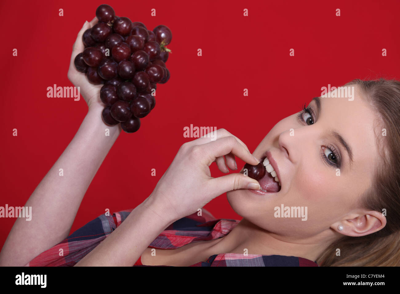 Donna di mangiare grappolo di uva rossa Foto Stock