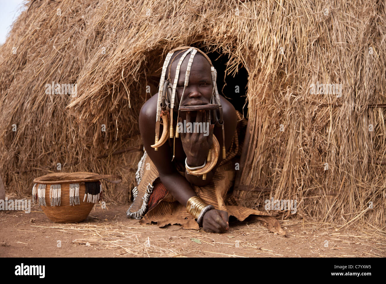 Mursi donna lasciando la sua casa tradizionale Jinka, Valle dell'Omo, Etiopia, Africa Foto Stock