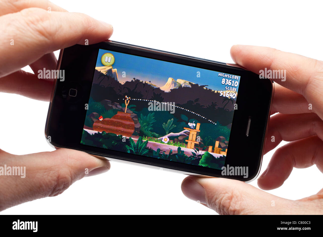 Le mani sono in possesso di un iPhone la riproduzione di Angry Birds game Foto Stock