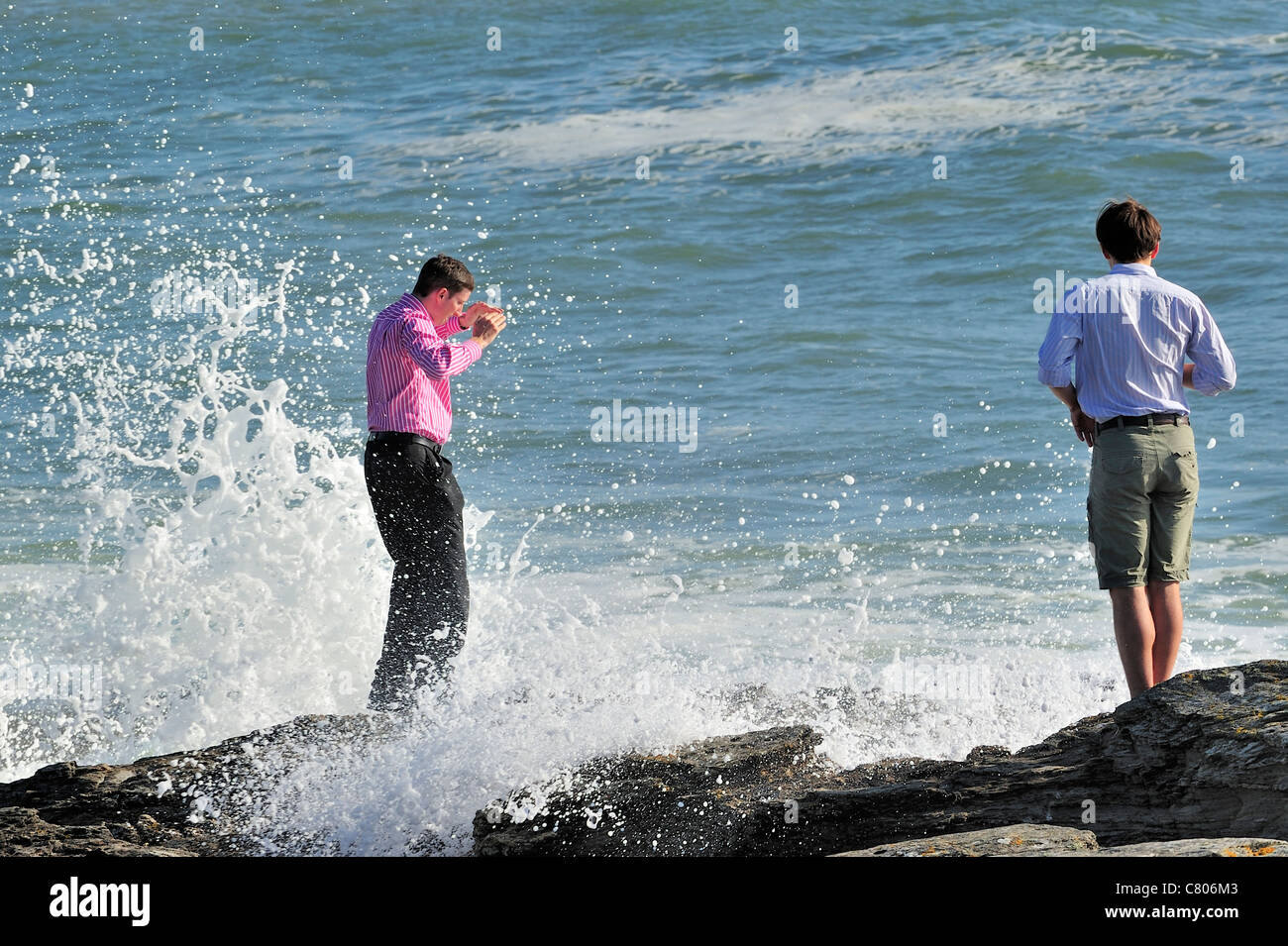 Tourist getting bagnati dalle onde che si infrangono sulle rocce, Pointe Saint-Gildas / Saint Gildas Point, Loire-Atlantique, Francia Foto Stock