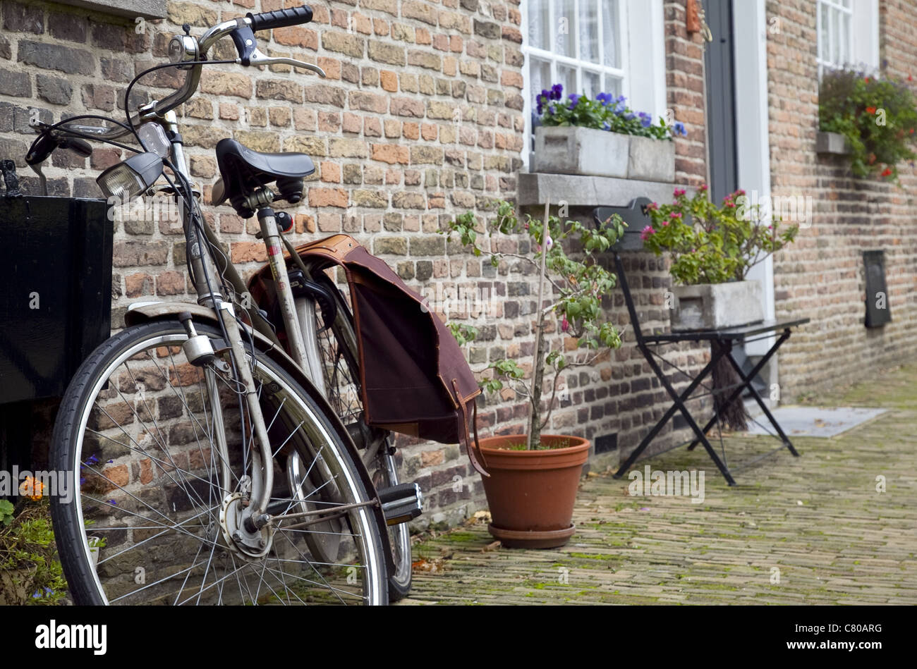 Una foto a colori in pane, Olanda, con un molto olandese sentire. Una bicicletta e fioriere sui davanzali contro una vecchia casa di mattoni. Foto Stock