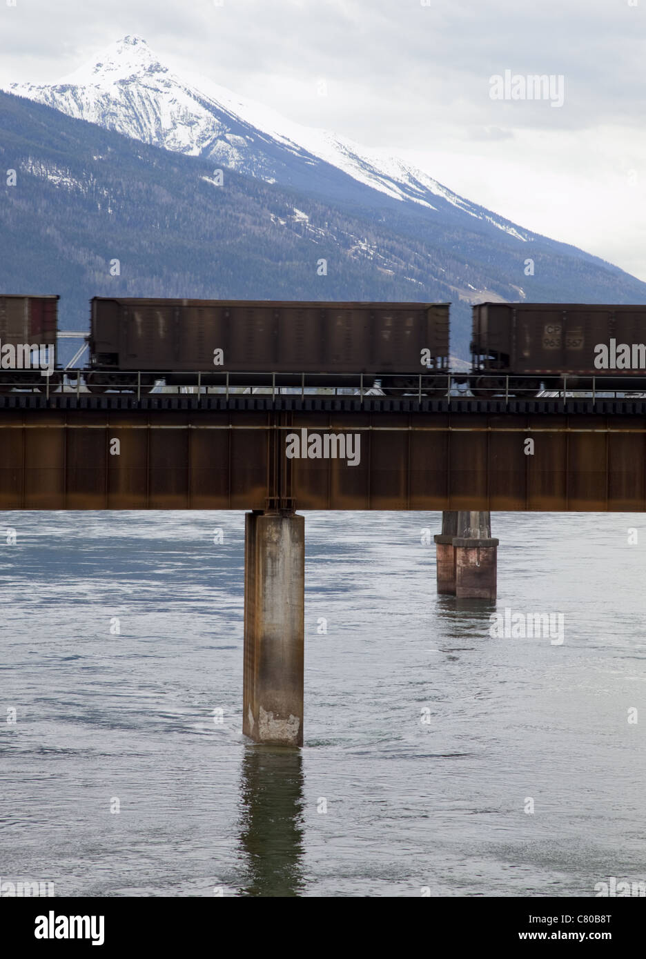 Fotografia a colori di un treno merci passando sopra il ponte di Revelstoke, BC, montagne rocciose della distanza Foto Stock