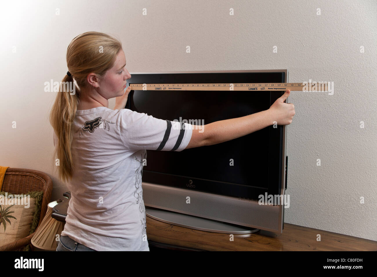 Ragazza adolescente misure le dimensioni di una TV 32 pollici schermo.  Signor © Myrleen Pearson Foto stock - Alamy