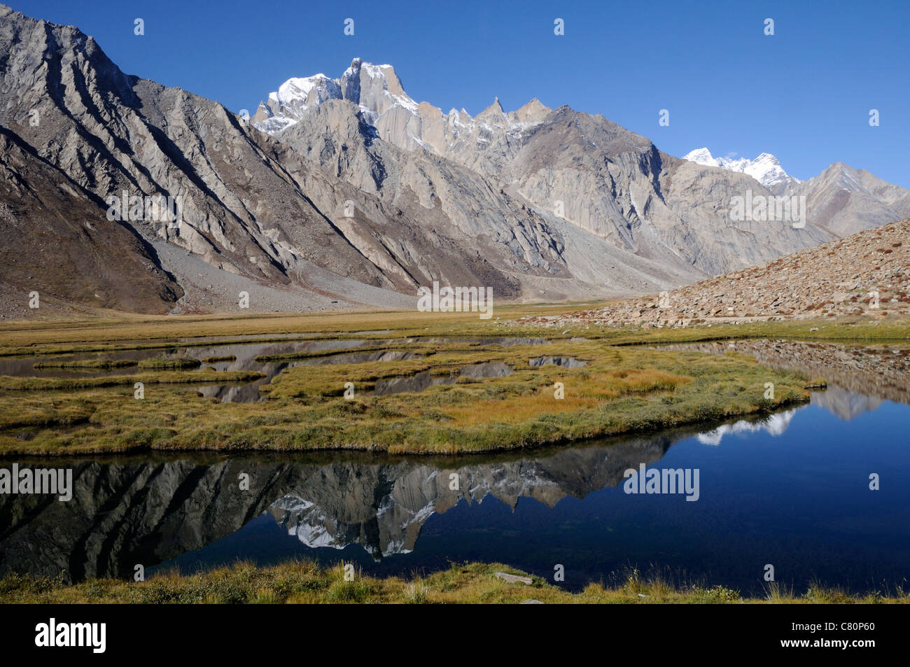 I picchi del Zanskar montagne riflesso in uno stagno a ovest della strada da Kargil nello Zanskar valley. Panikhar, Ladakh Foto Stock