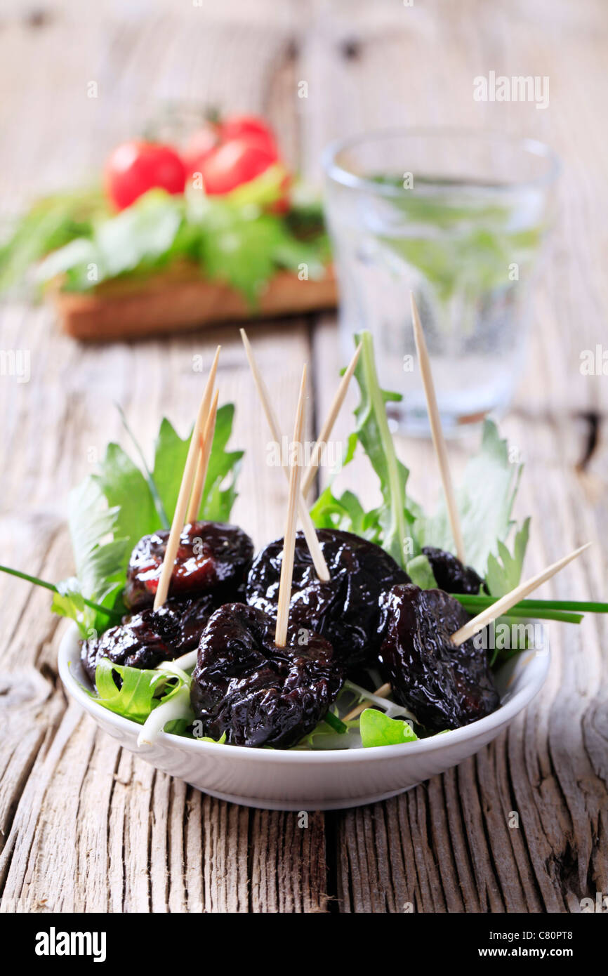 Le prugne secche vetrata su un nido di insalata verde Foto Stock
